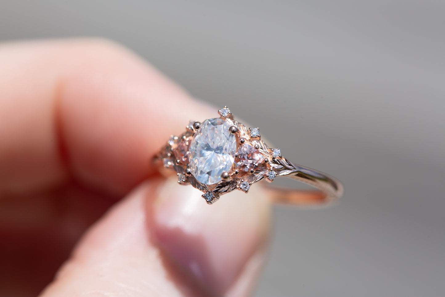 Woodland three stone setting with oval 7x5mm moissanite and lab peach sapphire sides