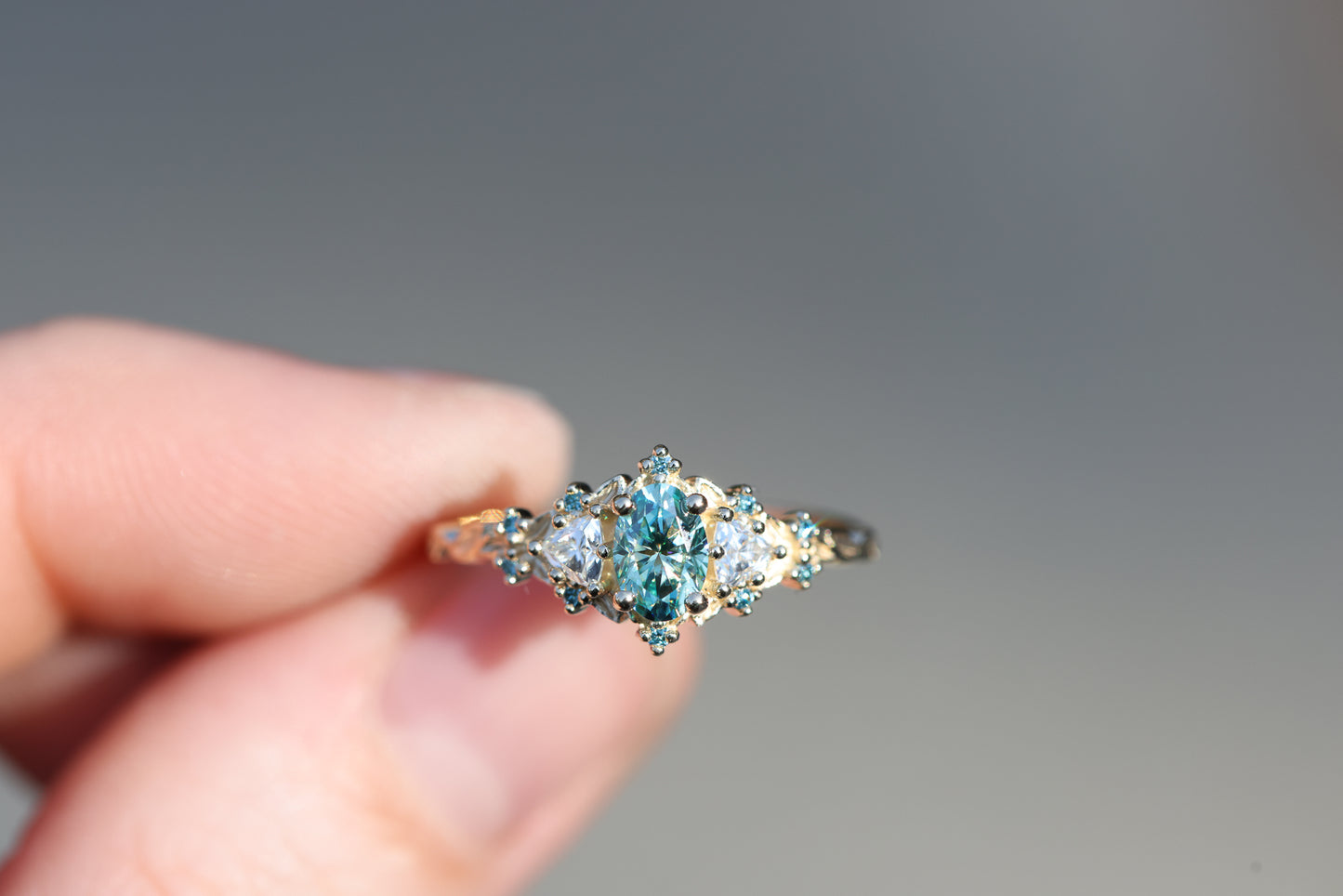 Briar rose three stone with oval teal moissanite and aqua diamonds